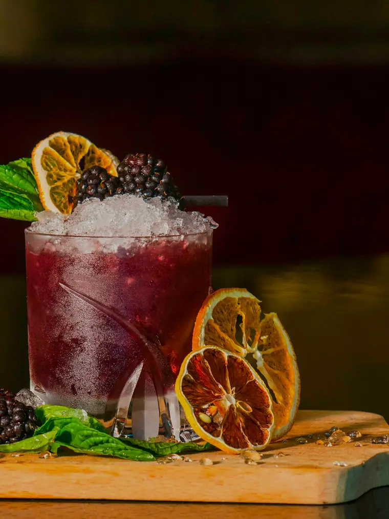 Cóctel de autor con hielo picado, cítricos deshidratados y frutos rojos